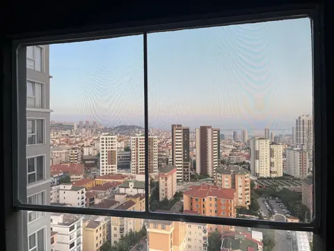 Şehir manzaralı yüksek katlı pencerede plise sineklik